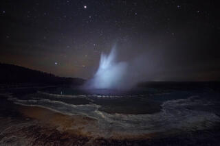 great fountain geyser in yellowstone national park erupting at night
