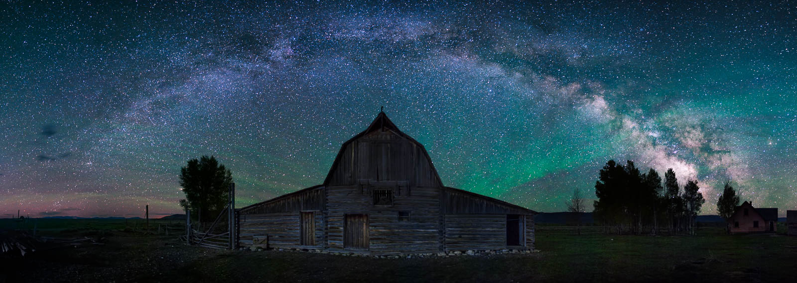 The milky way arcs over the North Moulton Barn in Grand Teton National Park with airglow burning brightly in the sky