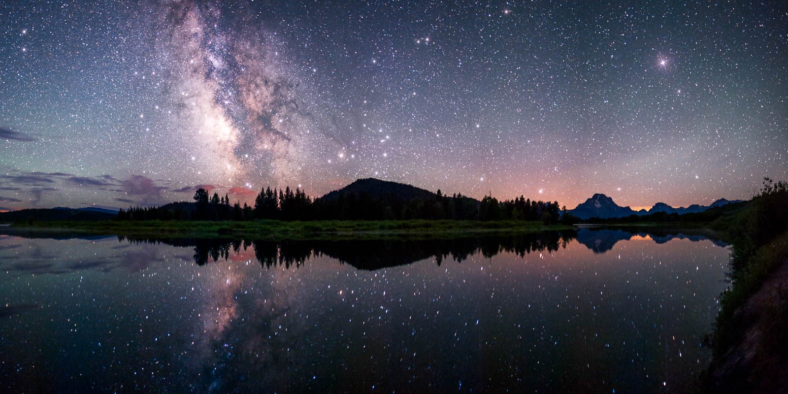 The milky way reflects in the Snake River at the famous Oxbow Bend in Grand Teton National Park